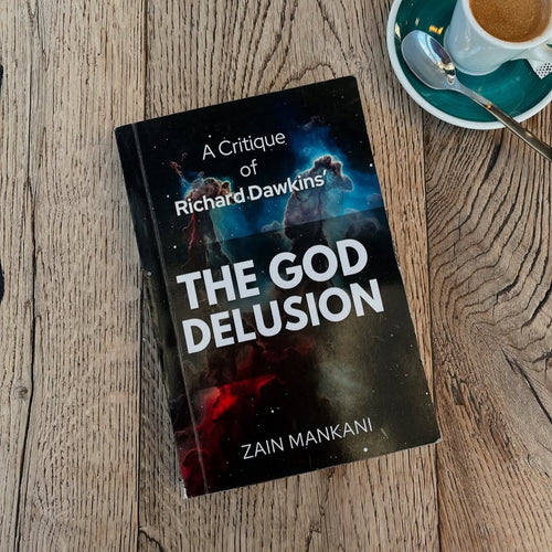 Book titled 'A Critique of The God Delusion' by Zain Mankani on a wooden surface with a cup of coffee.