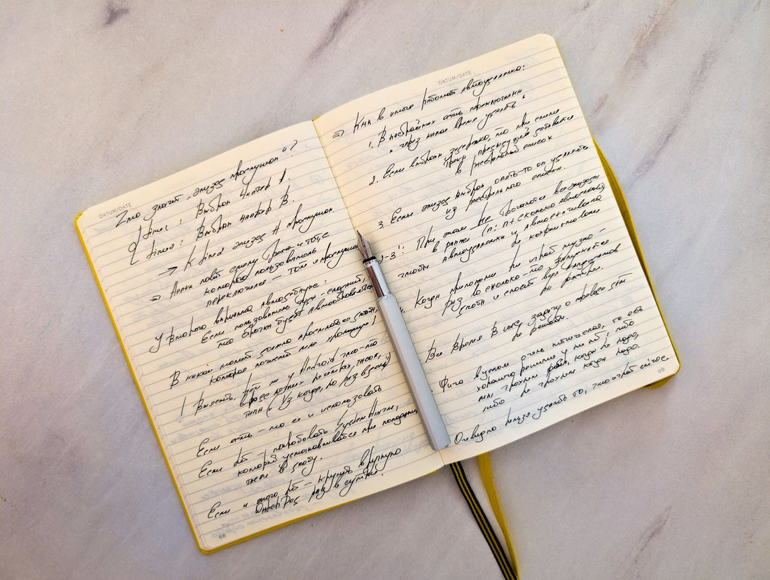 An open notebook filled with handwritten pages beside a pen, the drafting stage where most short stories take shape.