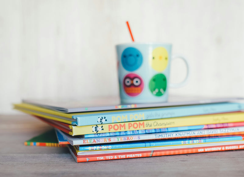 A stack of illustrated children's storybooks piled on a table, spines and covers facing out