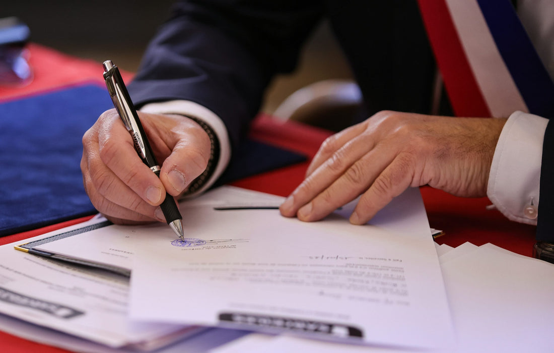 An author signing a publishing agreement at a desk, pen resting on the printed contract