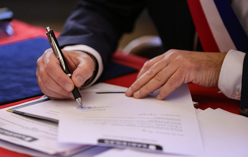 An author signing a publishing agreement at a desk, pen resting on the printed contract