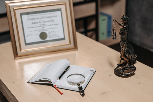 Open book, pen and official certificate on a bright desk suggesting legal paperwork