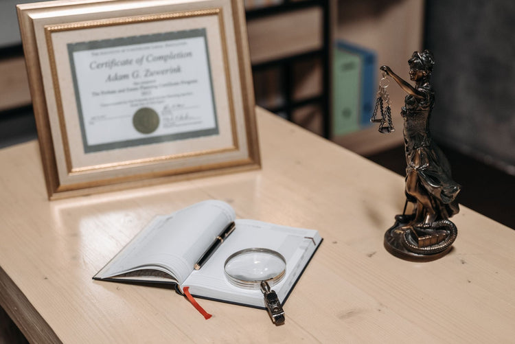 Open book, pen and official certificate on a bright desk suggesting legal paperwork