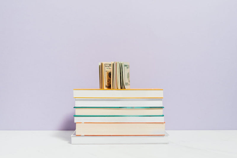 Banknotes resting on a stack of books, illustrating book royalties and author earnings