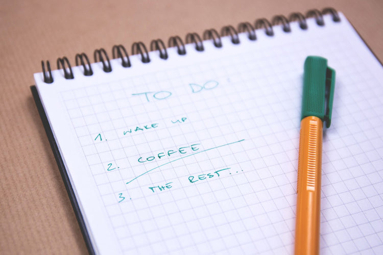 Handwritten checklist on a notebook with a pen on a bright desk