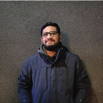 Person wearing a dark jacket against a textured wall